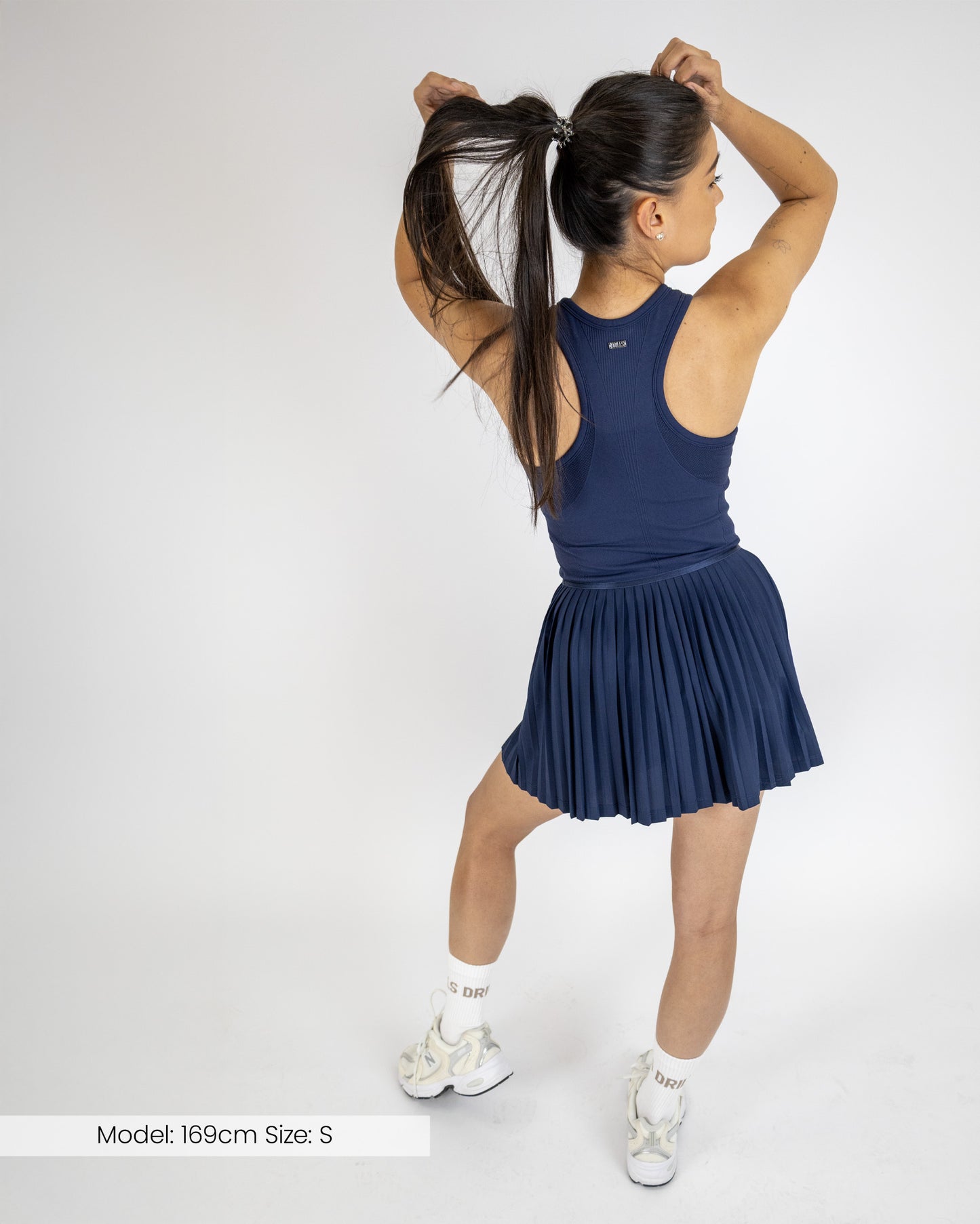 Model trägt das Tennisdress von DRILLS der Kollektion RACQUET in Navy Blau
