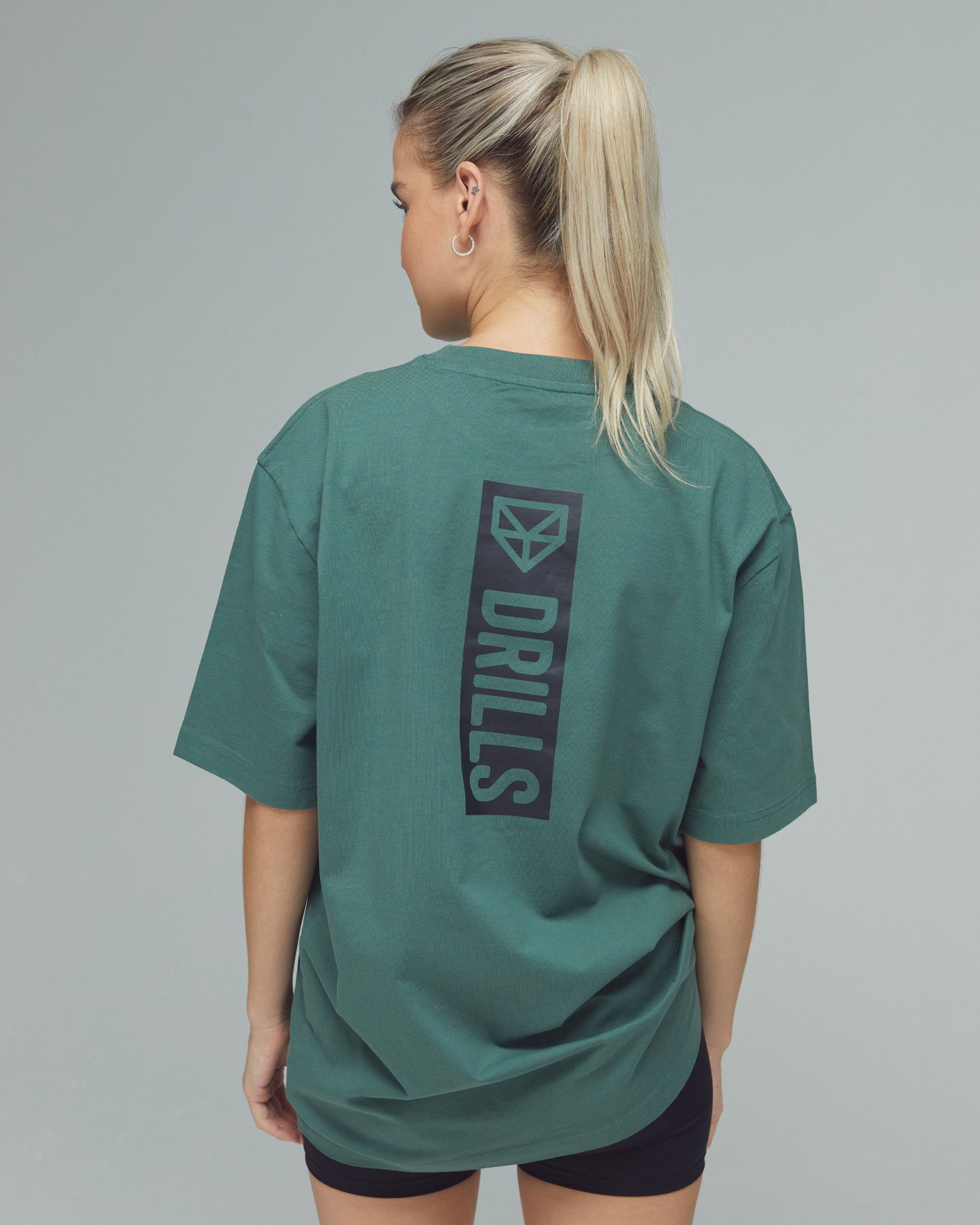 Model trägt das Vertical Graphic Tee von DRILLS in Dark Sage Green