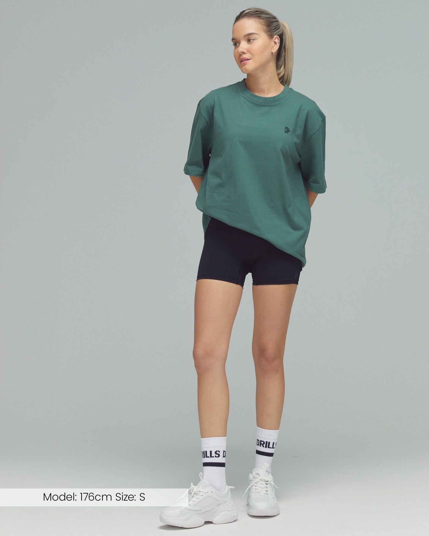 Model trägt das Vertical Graphic Tee von DRILLS in Dark Sage Green