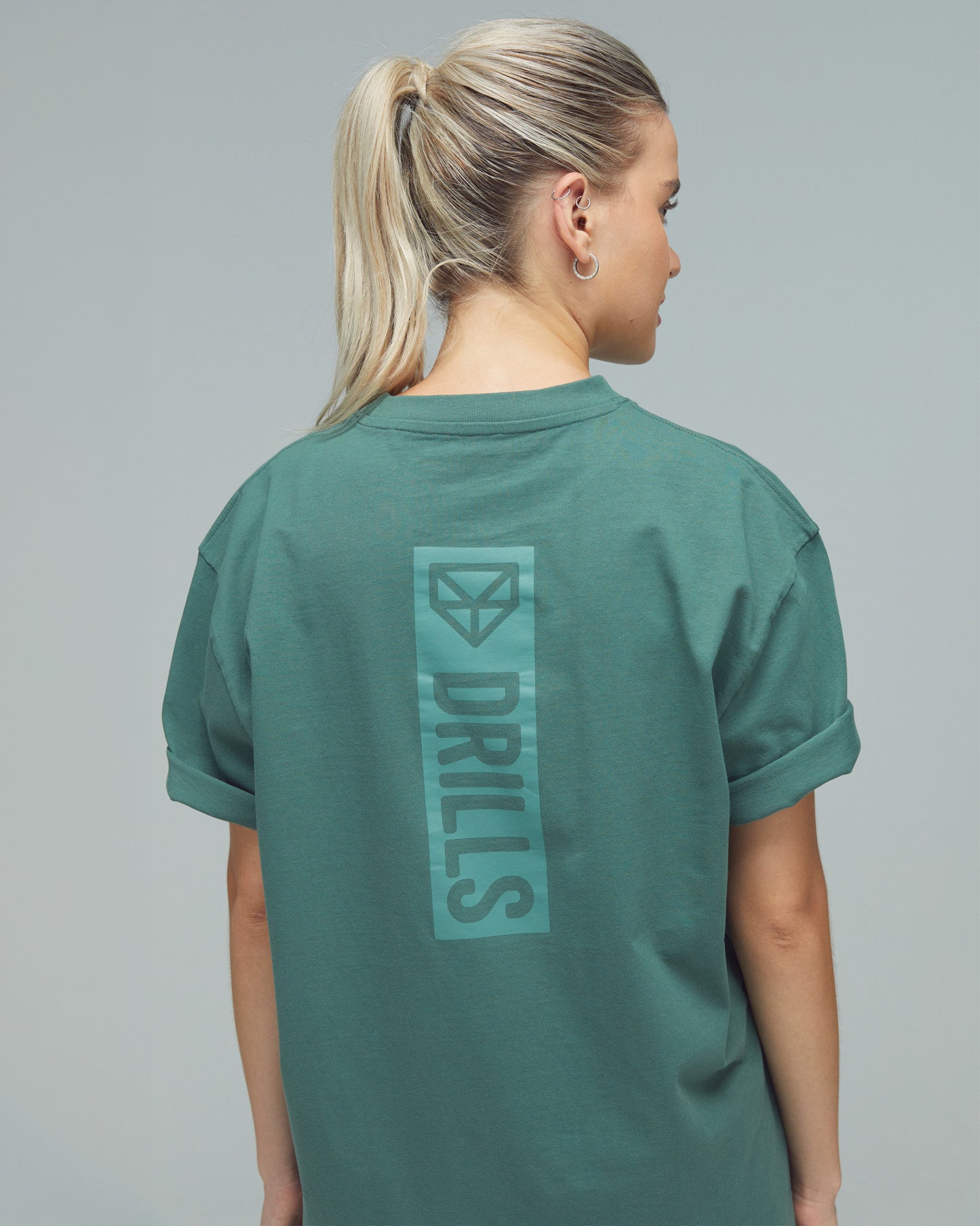 Model trägt das Vertical Graphic Tee von DRILLS in Dark Sage Green
