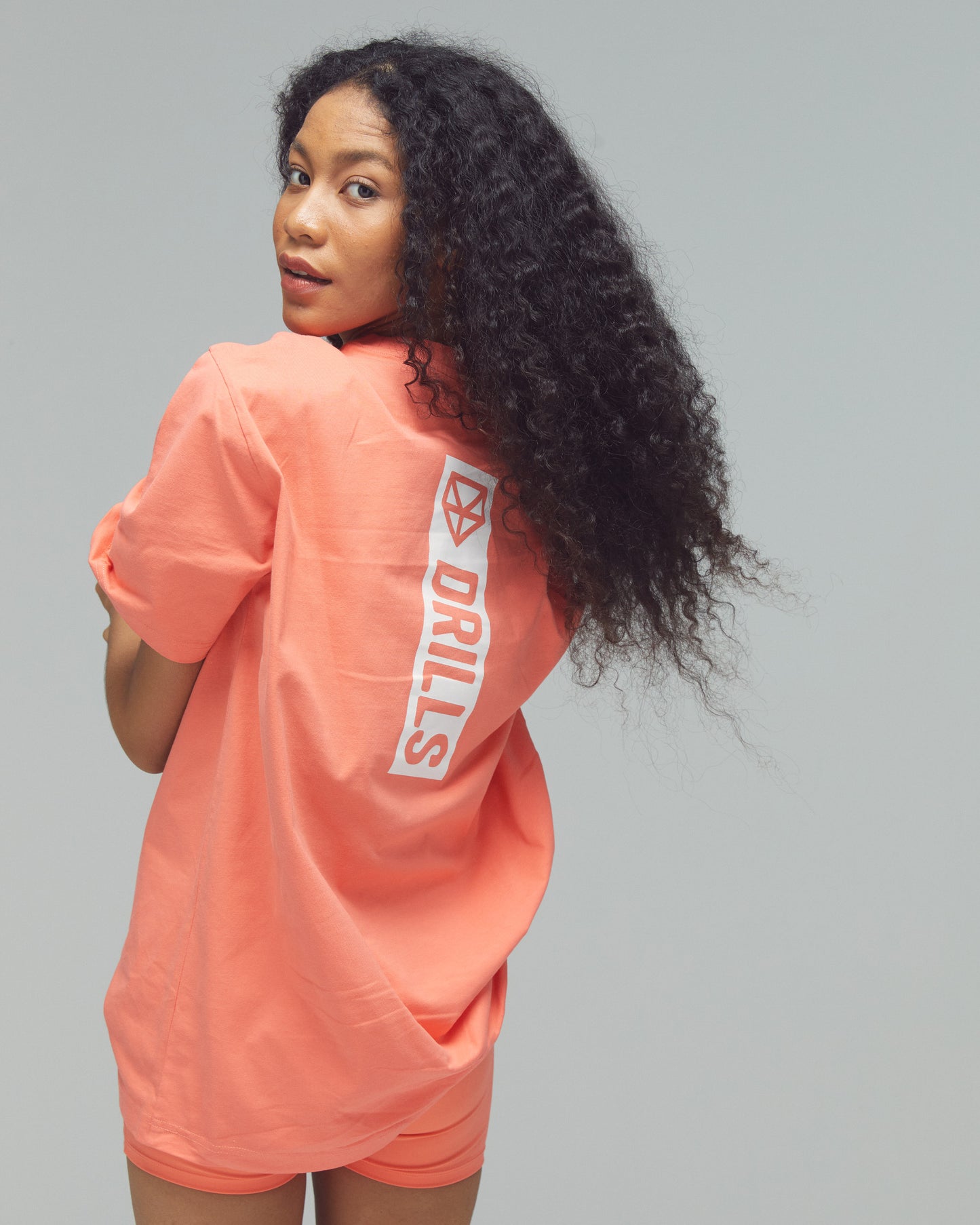 Model trägt das Vertical Graphic Tee von DRILLS in sunset glow