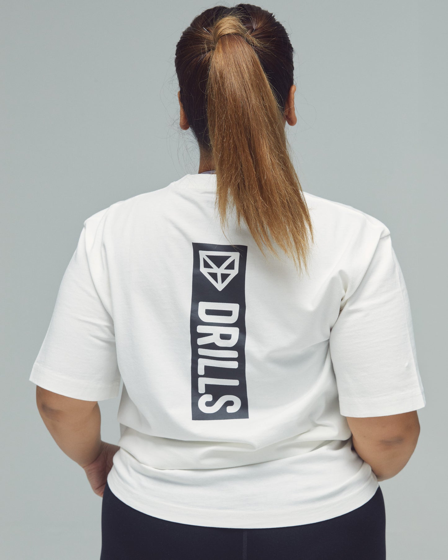 Model trägt das Vertical Graphic Tee von DRILLS in weiß