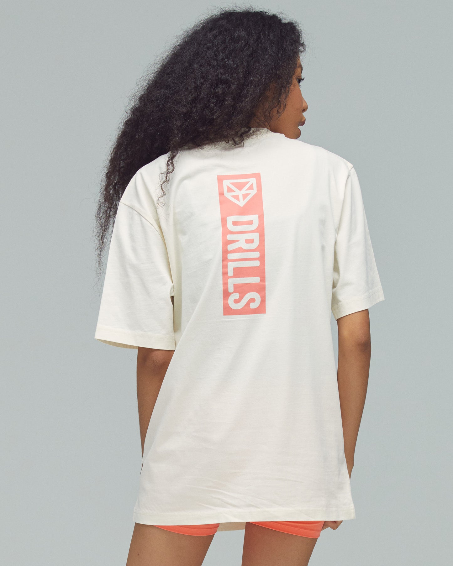 Model trägt das Vertical Graphic Tee von DRILLS in weiß - sunset glow