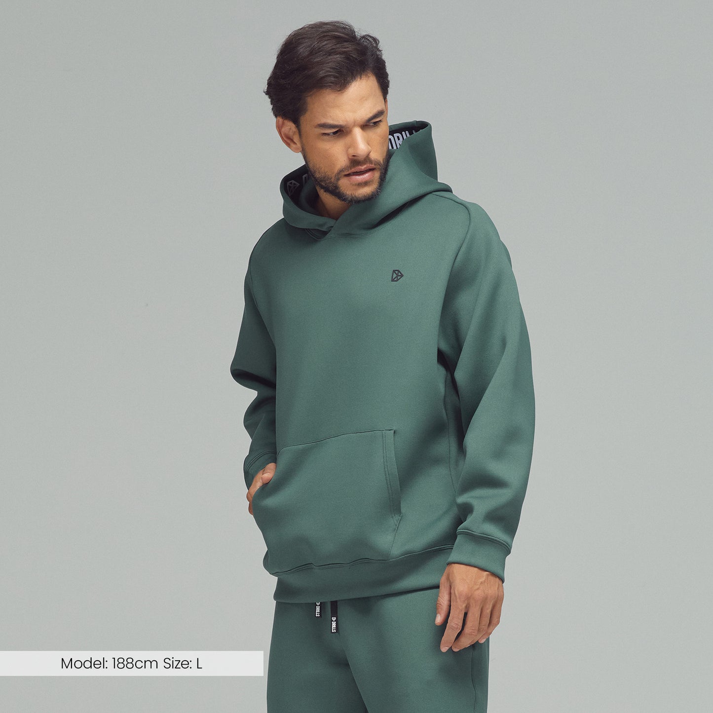 Model trägt den Hoodie von DRILLS in Dark Sage Green