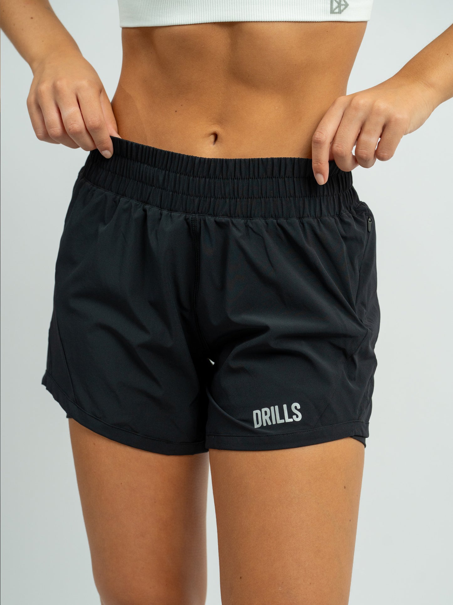 Model trägt die XFUNCTION 2-in-1 Laufhose von DRILLS in schwarz