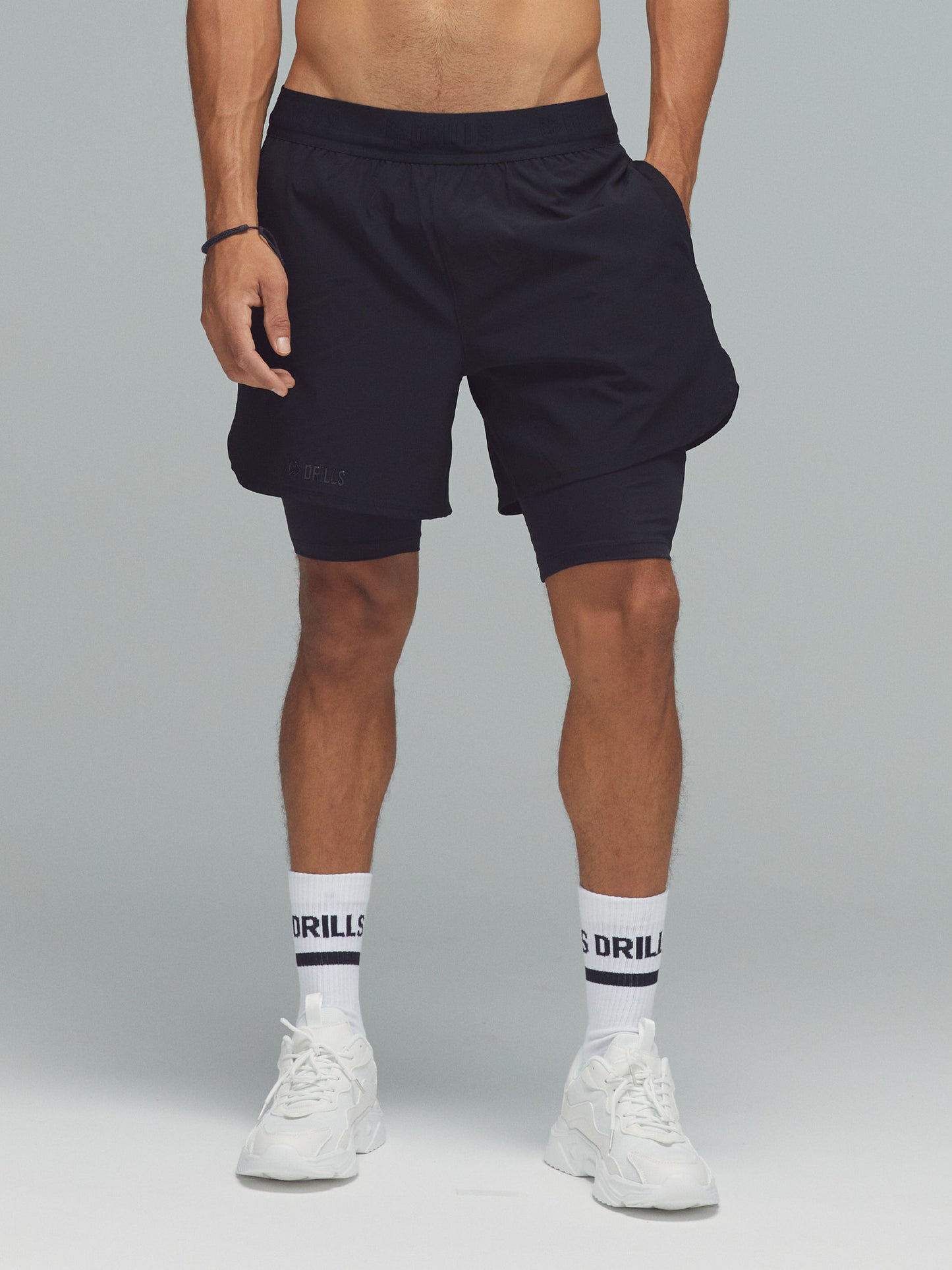 Model trägt die 2-in-1 Sportshorts von DRILLS in schwarz