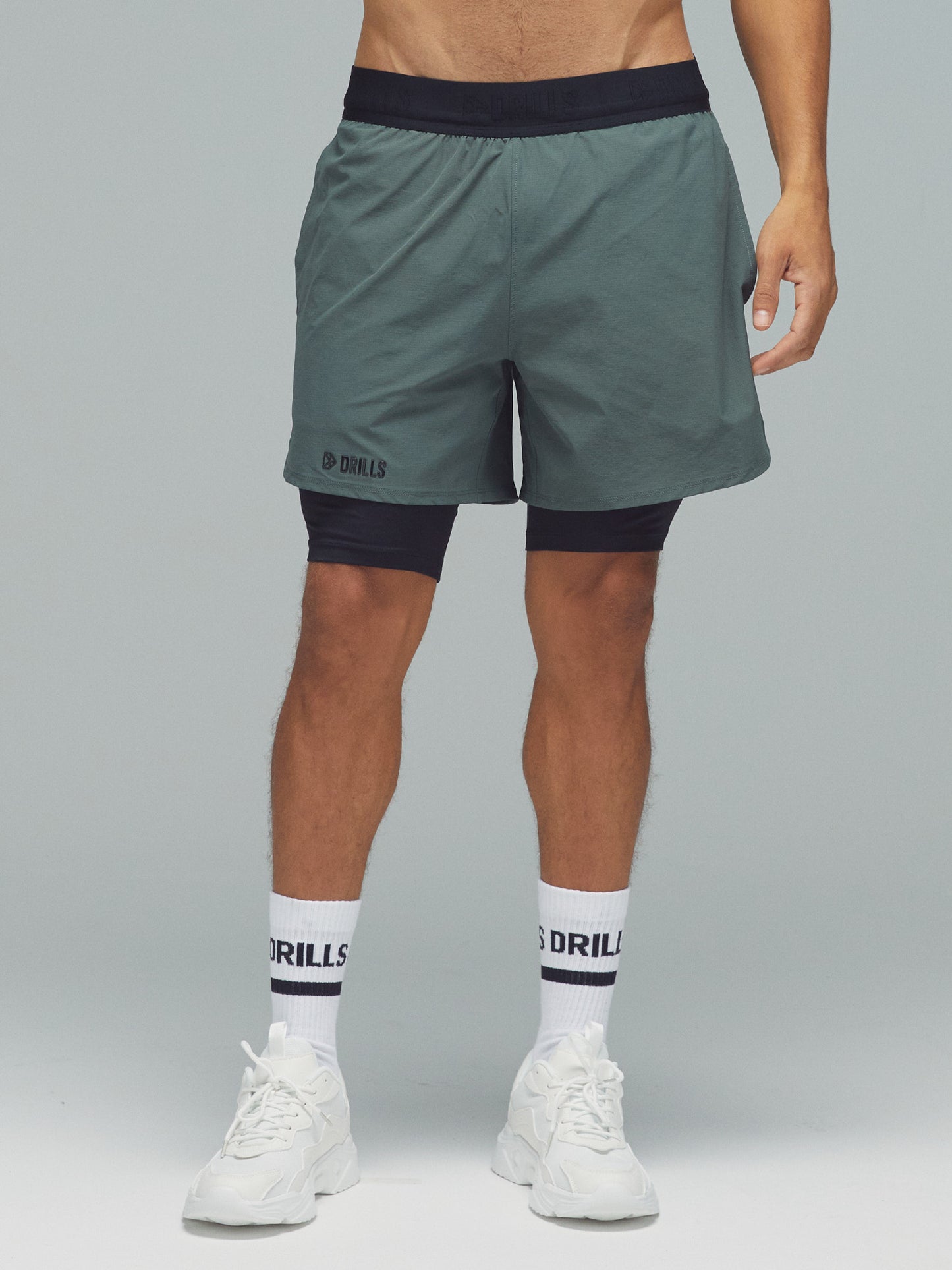 Model trägt die 2-in-1 Hose von DRILLS in Dark Sage Green